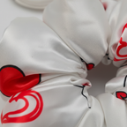 Close-up of white satin silk fabric with crown and heart print showing smooth luxurious texture – premium satin sleep gift set for women