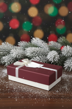 Burgundy red Christmas silk scarf gift box with white ribbon bow on festive holiday background with pine branches and bokeh lights - May Silk Co